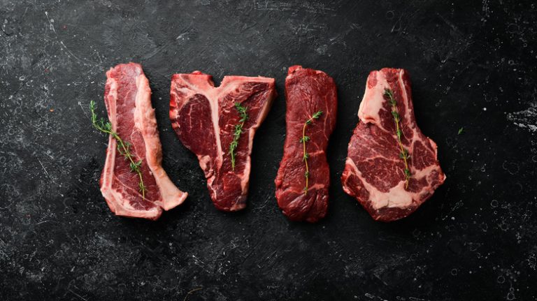 four cuts of raw steak with thyme