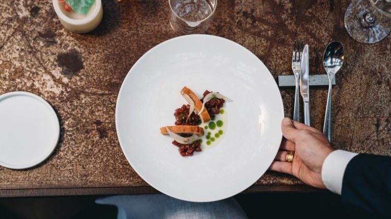 Waiter serving white plate